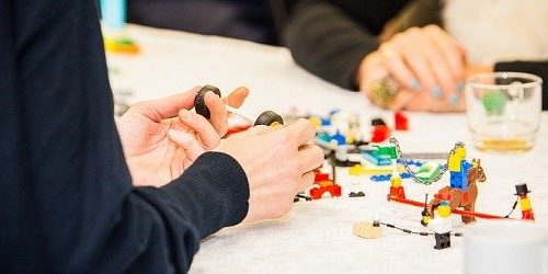 Handen van deelnemers aan de slag met Lego